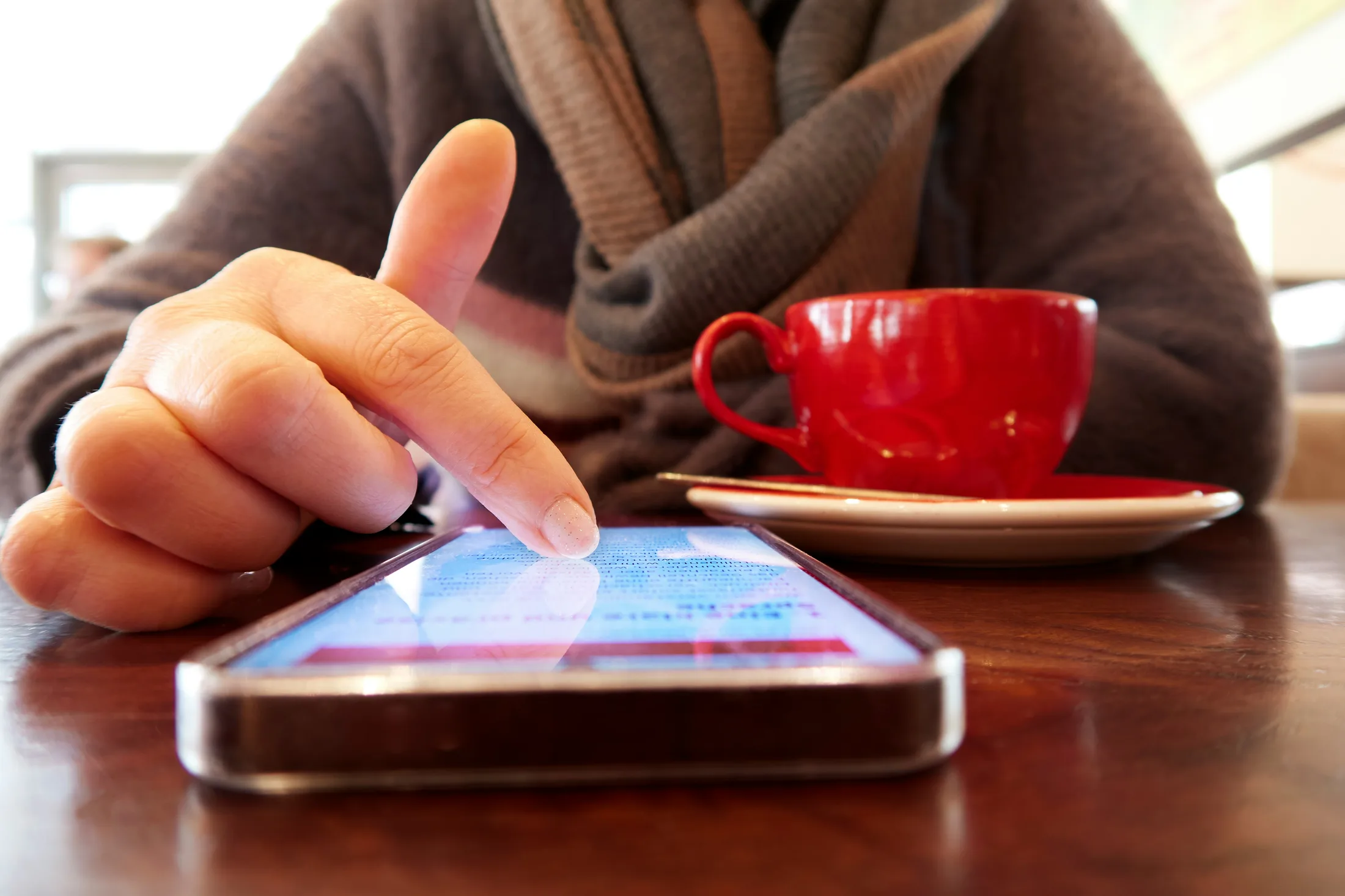 A person opening a SETU profile on a phone beside a red cup